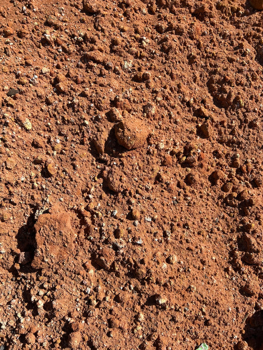 Close-up image of red sandy clay with a mix of fine particles and small rocky chunks